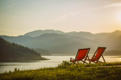 two chairs sitting in the grass near a body of water at Zoranovi konaci in Jevtići