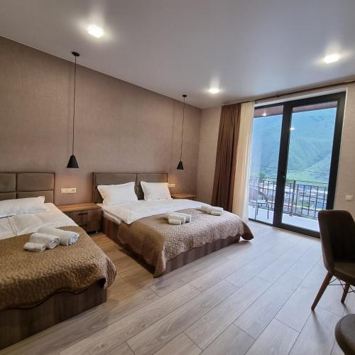 a bedroom with two beds and a large window at Hotel Sweet Night in Stepantsminda