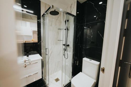 a black and white bathroom with a shower and a toilet at Apartamentos MK77 León - Palomera in León