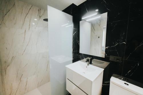 a bathroom with a white sink and a mirror at Apartamentos MK77 León - Palomera in León