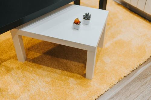 a white coffee table with a plant on top of a rug at Apartamentos MK77 León - Palomera in León