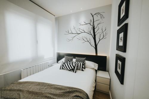 a bedroom with a bed with a tree on the wall at Apartamentos MK77 León - Palomera in León