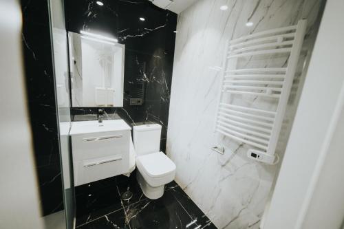 a black and white bathroom with a toilet and a sink at Apartamentos MK77 León - Palomera in León