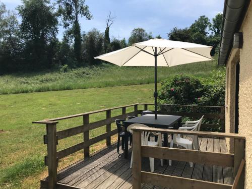 a table with an umbrella on a deck at Le repaire des hérissons Vallée de Rabais in Virton