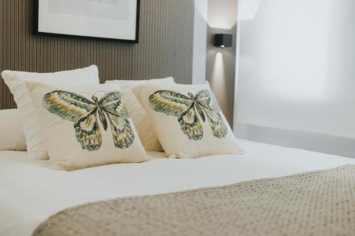 a bed with pillows with butterfly pillows on it at Apartamentos MK77 León - Palomera in León