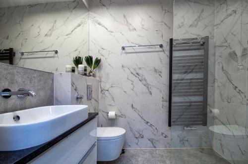 biała łazienka z umywalką i toaletą w obiekcie ApartPark ALBUS 401 SEA VIEW above the trees w Świnoujściu