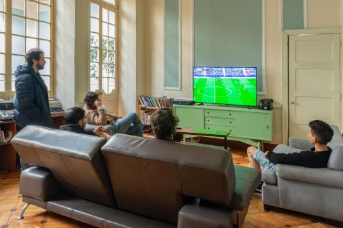 un grupo de personas sentadas en una sala de estar viendo televisión en Hostal R10, en Bogotá