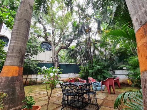 a patio with red chairs and a table and trees at Hostel Lifespace- Garden Bungalow with Pods, CoWork & Cafe in Pune
