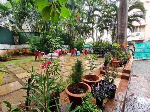 a garden with potted plants and tables and chairs at Hostel Lifespace- Garden Bungalow with Pods, CoWork & Cafe in Pune