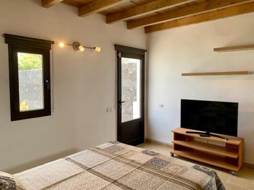 a bedroom with a bed and a flat screen tv at Casa Nepal in Playa Blanca
