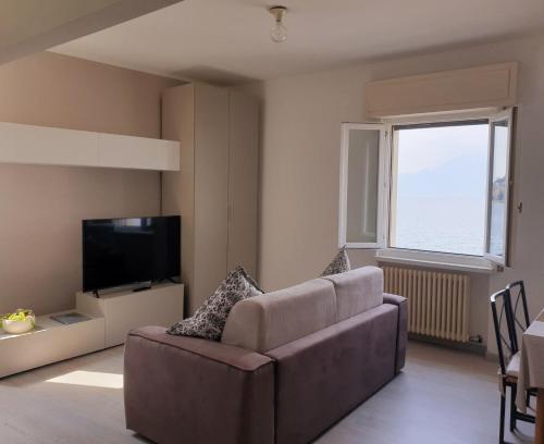 uma sala de estar com um sofá e uma televisão em Assenza Lake Front Sweet Apartment em Brenzone sul Garda