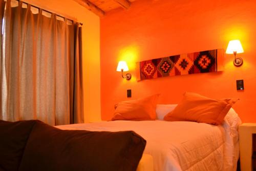 a bedroom with orange walls and a bed with orange pillows at Cabañas Chacras del Arroyo Vidal in Carpintería