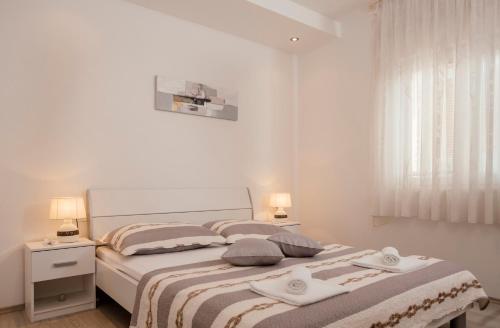 a white bedroom with a bed with two pillows at Apartments Kolovrat in Podstrana