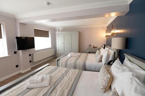 a hotel room with two beds and a flat screen tv at The Olde Bell, BW Signature Collection in Marlow