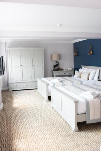 a bedroom with four white beds and a blue wall at The Olde Bell, BW Signature Collection in Marlow