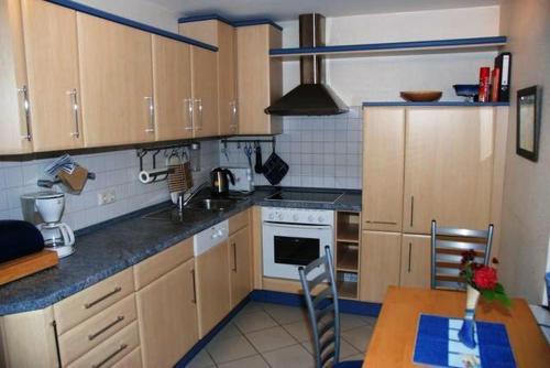 a kitchen with wooden cabinets and a table and a stove at Fenster in Kaltenhof