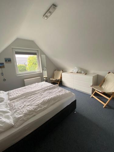 a bedroom with a bed and two chairs and a window at Fenster in Kaltenhof