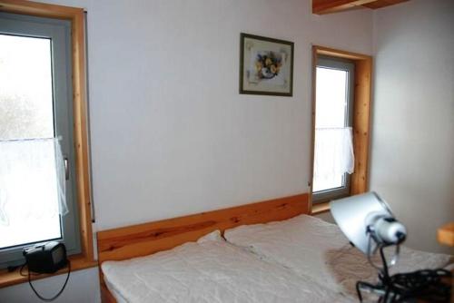 a bedroom with a white bed and two windows at Hexenhäuschen in Kaltenhof