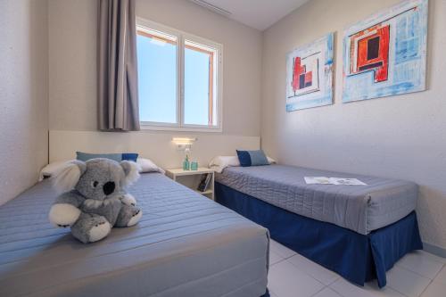 a teddy bear sitting on a bed in a room at Apartamentos Estival Park in La Pineda