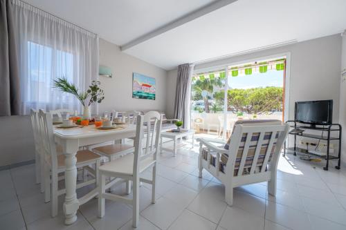 a white dining room with a table and chairs at Apartamentos Estival Park in La Pineda