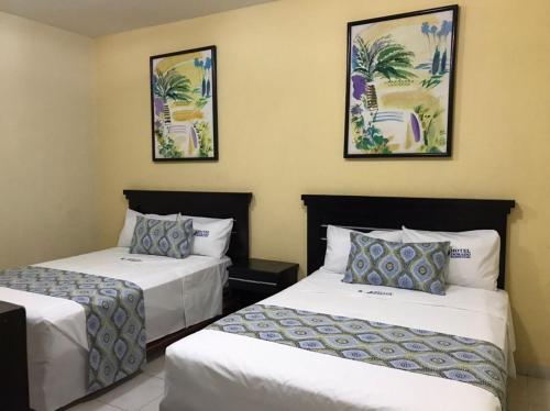 a hotel room with two beds and two pictures on the wall at Hotel Dorado a una calle de Playa Regatas y el Malecon in Veracruz
