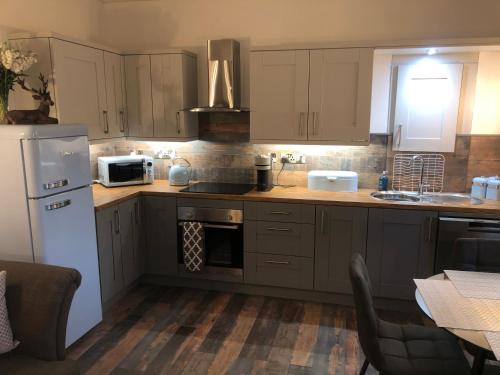 een keuken met bruine kasten en een witte koelkast bij The Coop in Castle Douglas