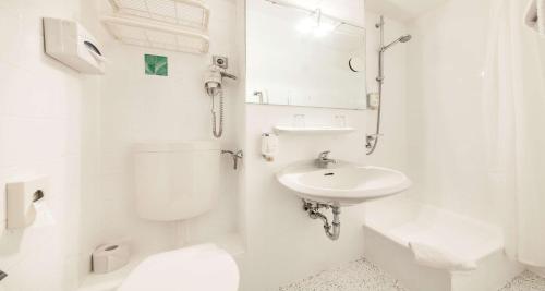 a white bathroom with a toilet and a sink at Sure Hotel by Best Western Muenchen Hauptbahnhof in Munich