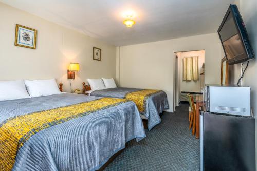 a hotel room with two beds and a flat screen tv at Parkway Inn in Waynesville