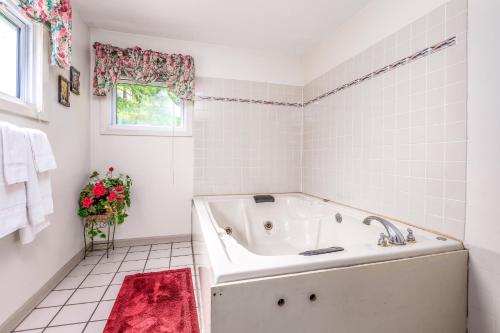 Baño blanco con bañera y alfombra roja en Parkway Inn, en Waynesville