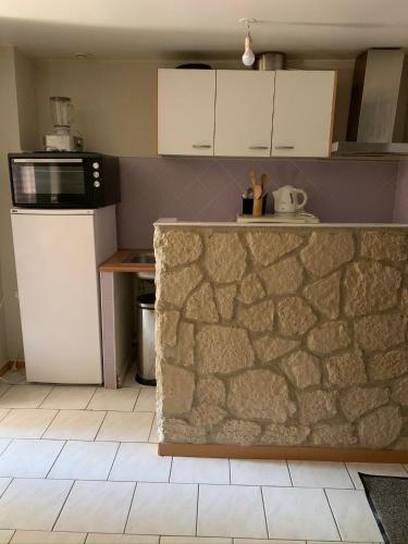 a kitchen with a stone counter and a microwave at Petit cocon in Château-Chinon