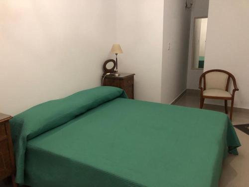 a bedroom with a green bed and a chair at URBANO TAJAMAR in Alta Gracia