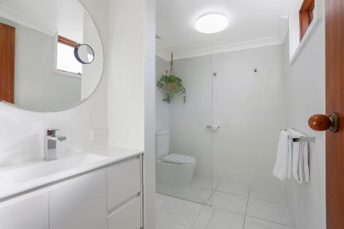 a white bathroom with a shower and a sink at Waves Motel and Apartments in Warrnambool