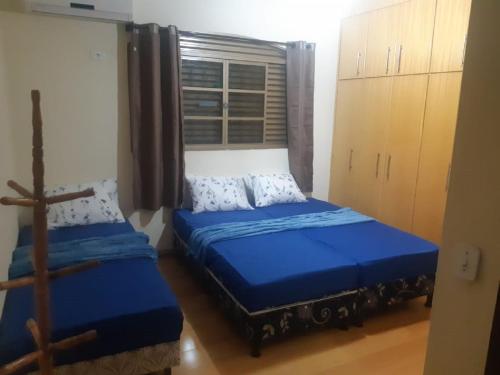 a bedroom with two beds and a window at Cascais Quartos & Suítes in Maringá