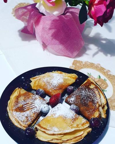 a plate of pancakes and berries on a table with flowers at Vila Reni Risi in Ksamil