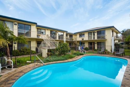 a swimming pool in front of a building at Ocean Drive Apartments in Merimbula