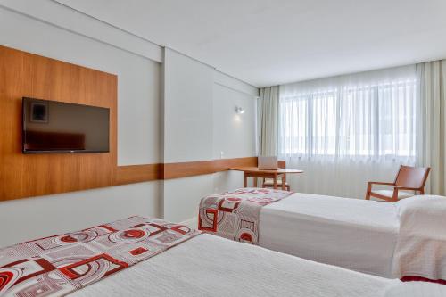 um quarto de hotel com duas camas e uma televisão de ecrã plano em Best Hotel Sobral em Sobral