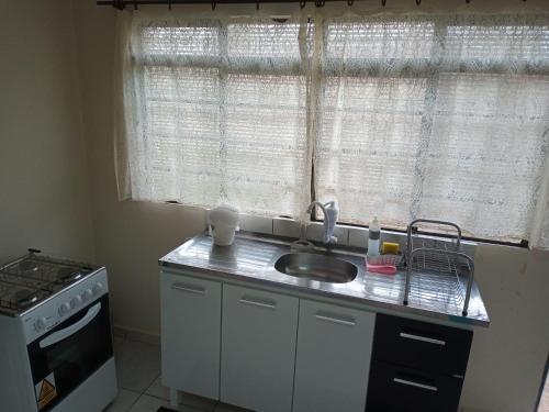 uma cozinha com um lavatório, um fogão e uma janela em Residencial Joed 4 em Dourados