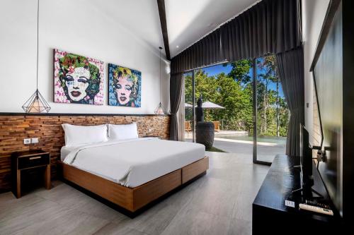 een slaapkamer met een bed en een televisie. bij Villa Mulia by BaliSuperHost in Ubud