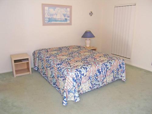 een slaapkamer met een bed en een tafel met een lamp bij ORSO1O - Water View House in Greenwell Point