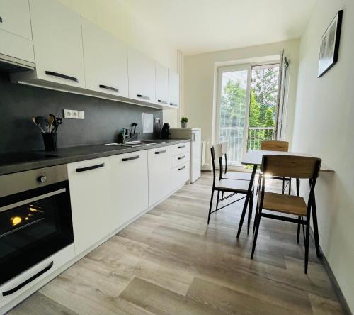 a kitchen with white cabinets and a table and chairs at ZAROHEM 2 bedrooms APARTMENT in center with balcony in Brno
