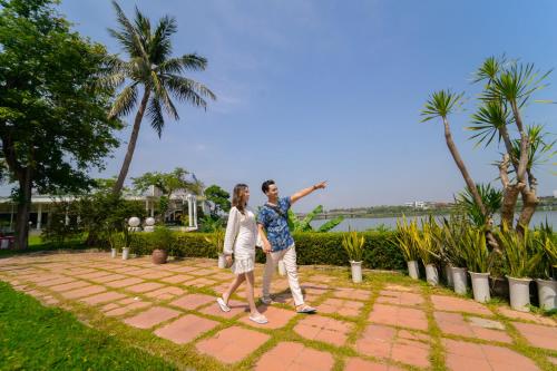 
a man and a woman standing on top of a lush green hillside at Century Riverside Hue in Hue
