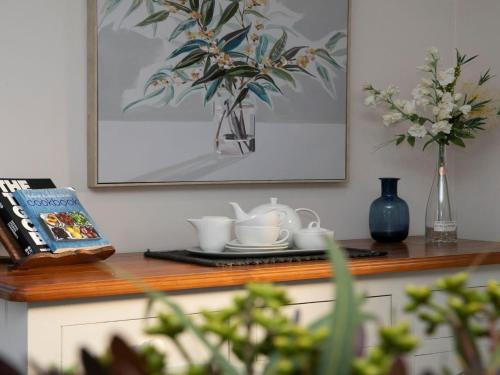 a table with cups and a vase with flowers on it at The Nook in Bowral