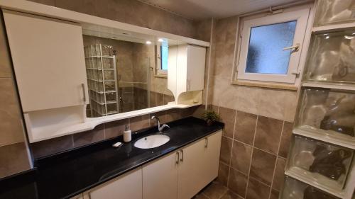 La salle de bains est pourvue d'un lavabo et d'un miroir. dans l'établissement Уютная вилла с шикарным панорамным видом, à Alanya