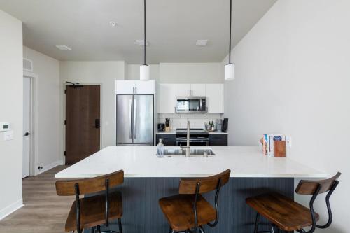 a kitchen with a large white island with chairs at East Side Luxury 1BR Apt - Near Brady St with Balcony and Lounge - Sleeps 4 in Milwaukee