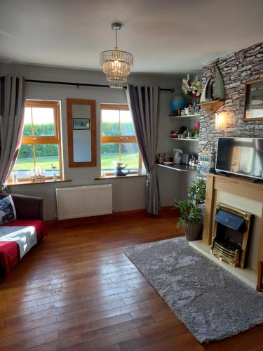 a living room with a fireplace and a tv at A New U Country Cottage in Valentia Island