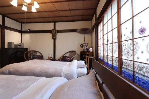 two beds in a room with large windows at Shanti House Sakaiminato in Sakaiminato