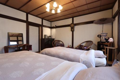 a bedroom with two beds and chairs and a ceiling at Shanti House Sakaiminato in Sakaiminato