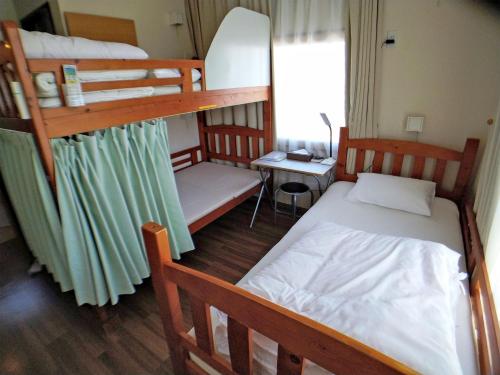 a bedroom with two bunk beds and a desk at Hiroshima Saijo Youth Hostel in Higashihiroshima