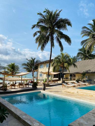 a swimming pool with palm trees and a building at Paje Beach Apartments & Hotel in Paje