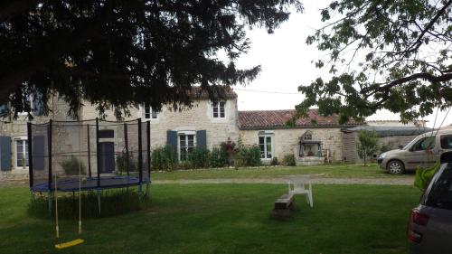 a yard with a trampoline in front of a house at Le Logis du Bouil in Champagne